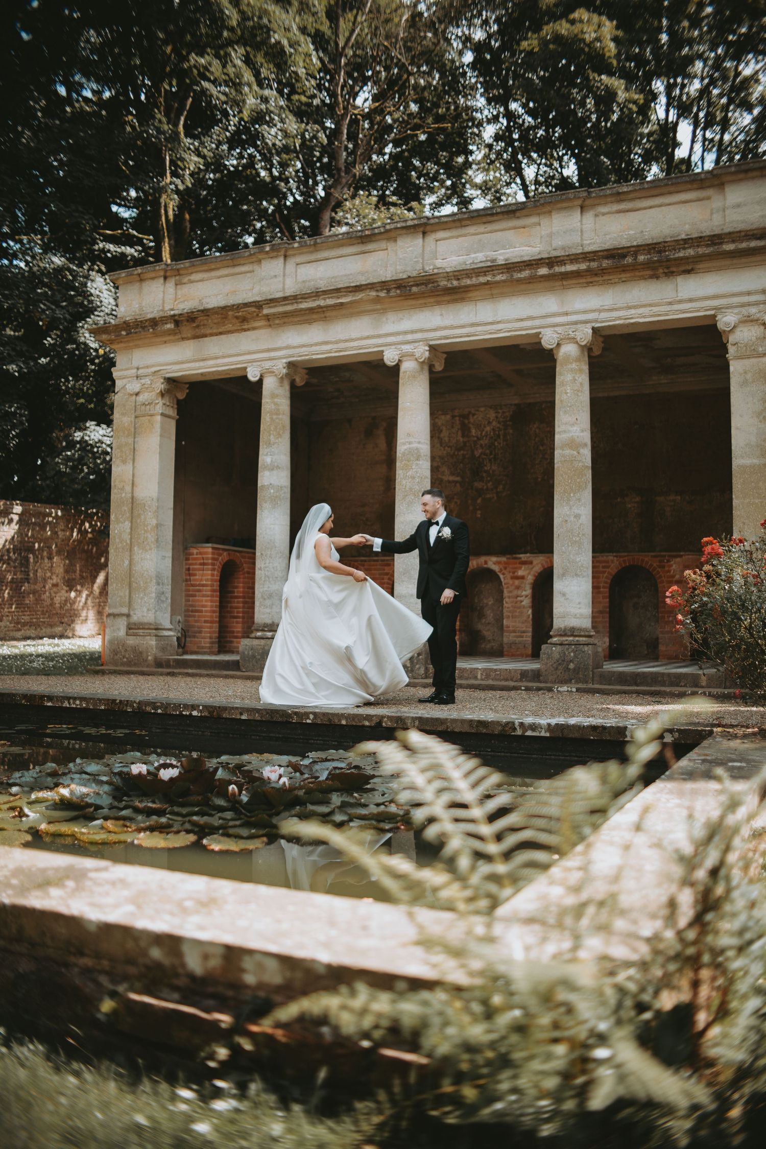 A wedding photo session in a classical colonnade with stone pillars and natural outdoor lighting.