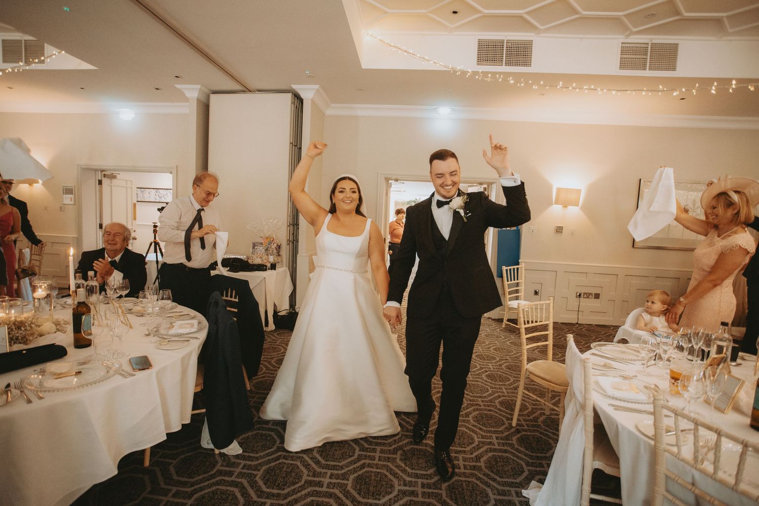 Wedding celebration in a banquet hall with guests dancing and celebrating.