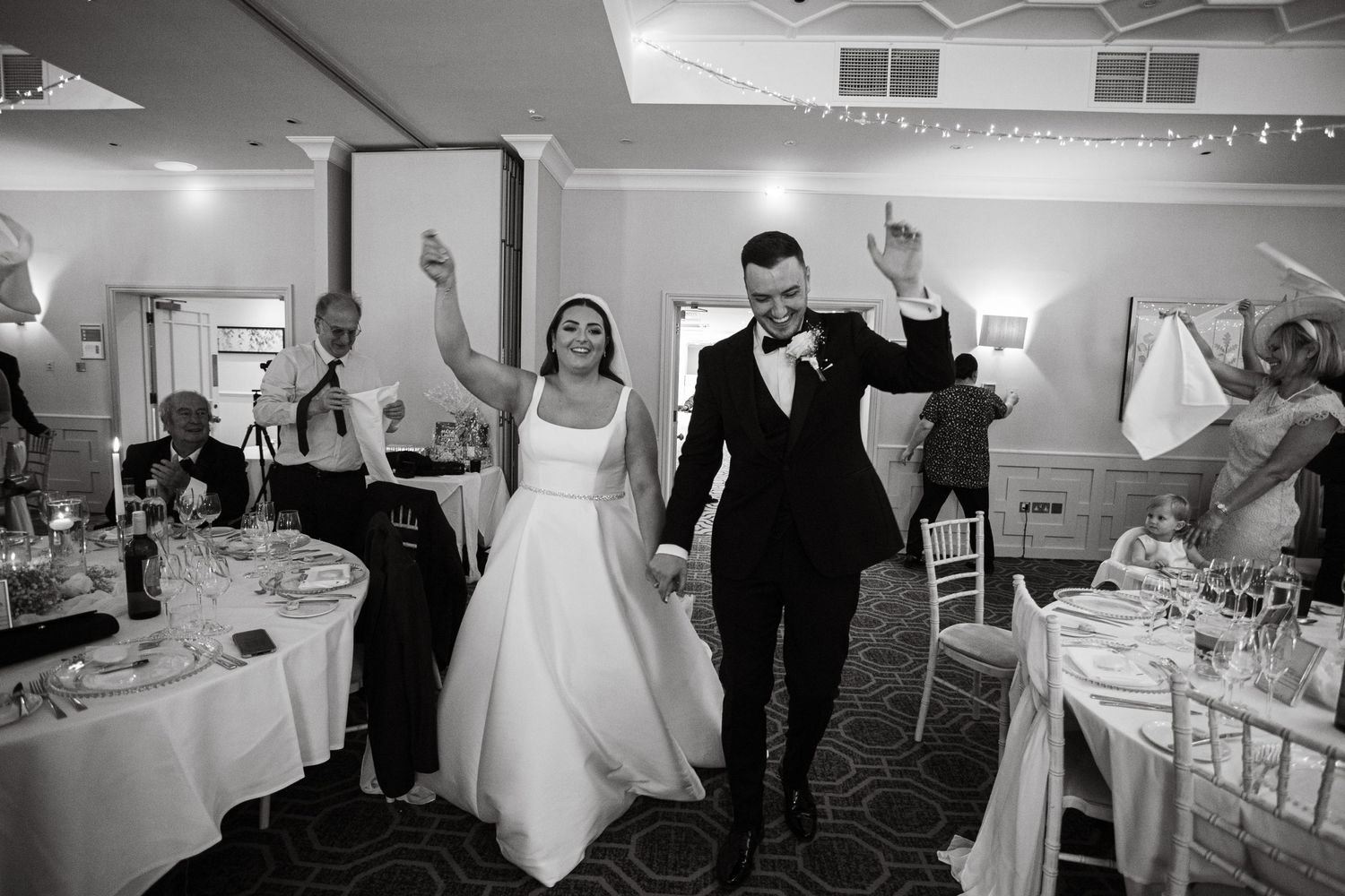 Wedding reception venue with elegant table settings and festive lighting.