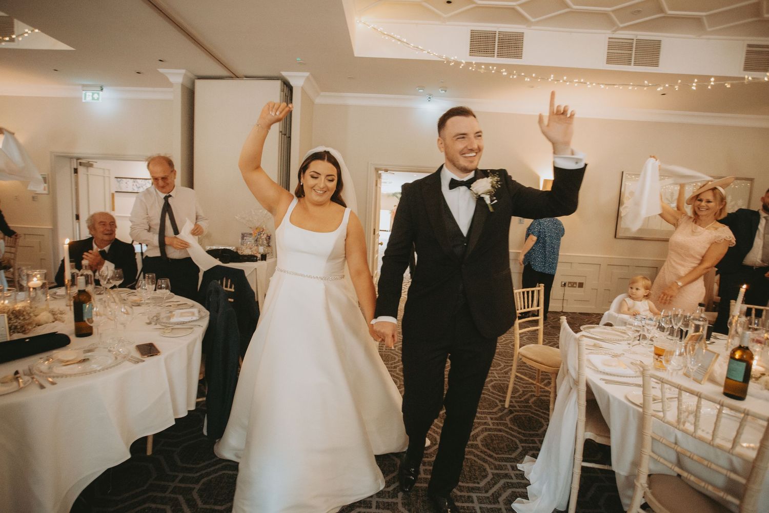 Joyful wedding reception scene with dancing and celebration in an elegant indoor venue.
