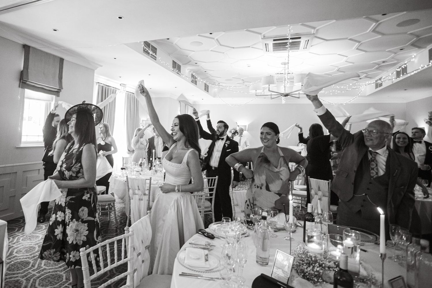 Panoramic view of a wedding reception with guests celebrating in an elegant ballroom.