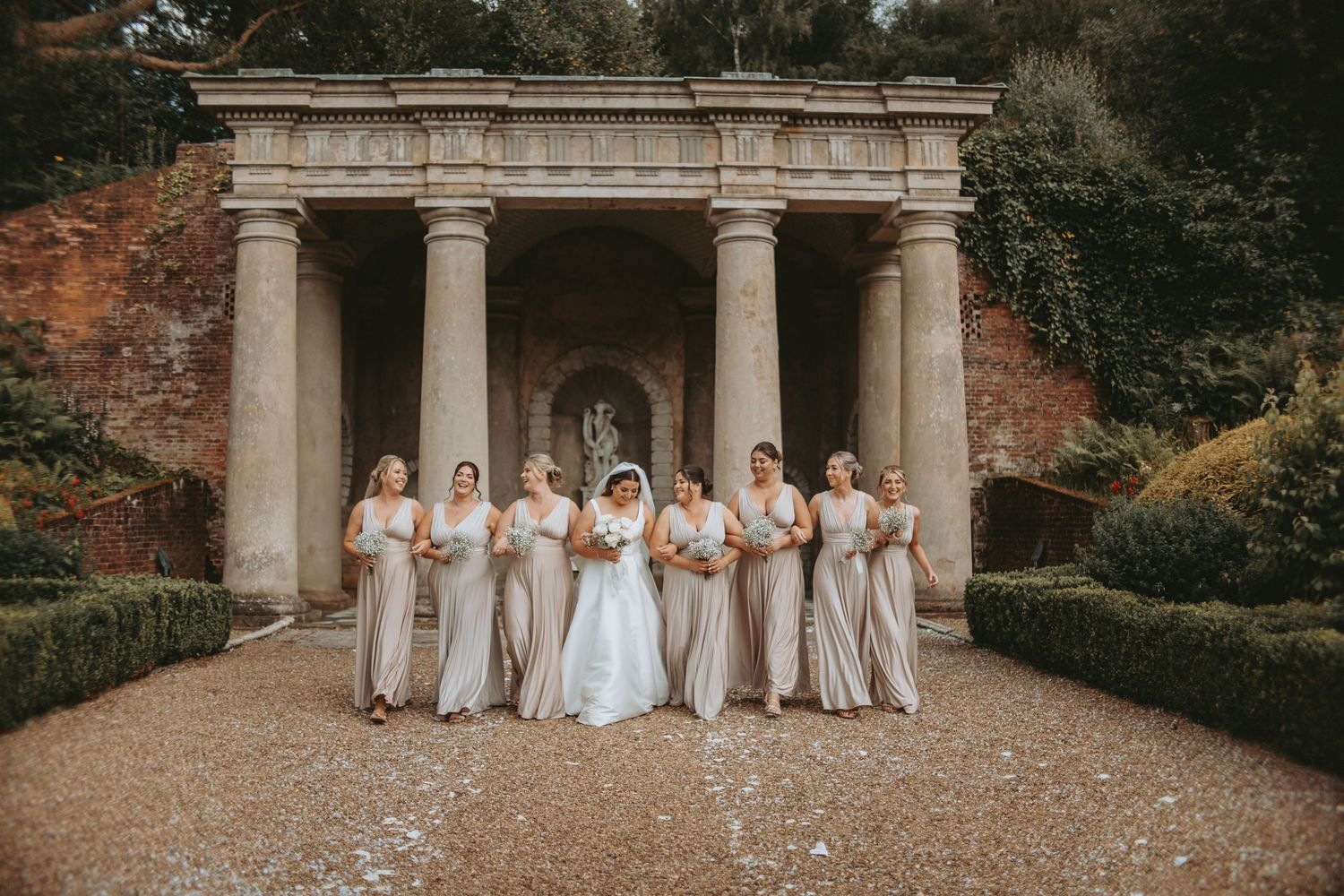 Wedding party poses in front of a grand columned building entrance with classic architecture.