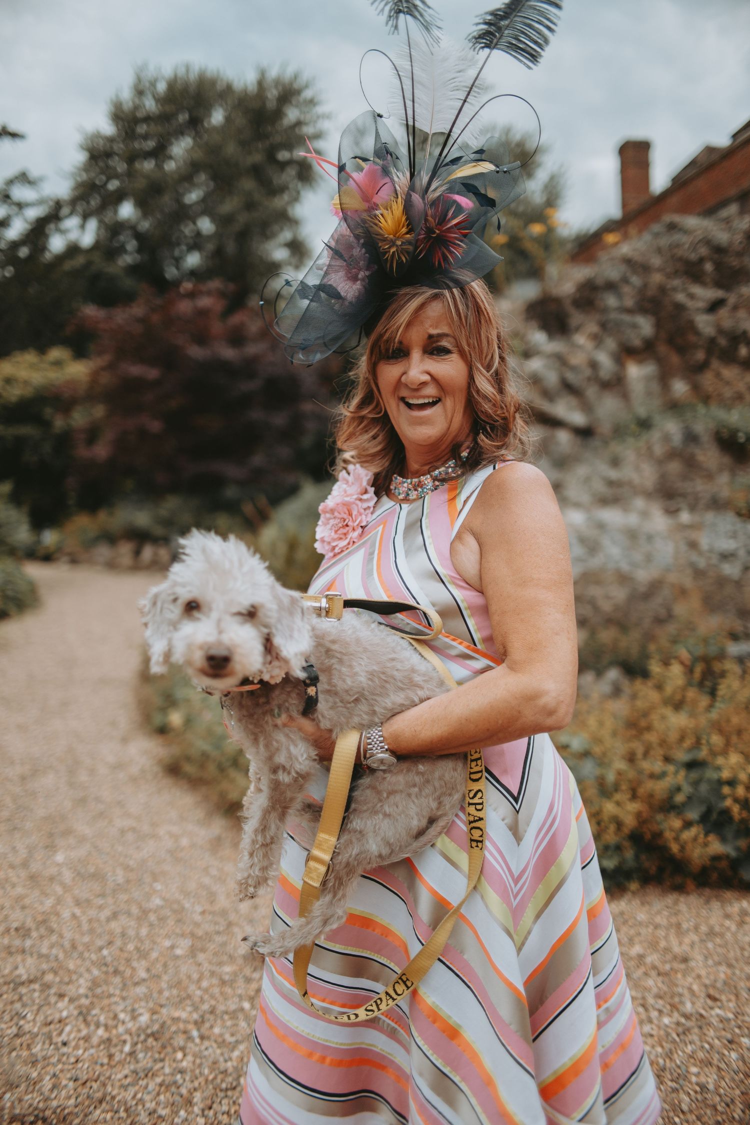 A festive outfit with a decorative hat and striped dress while holding a small white dog.