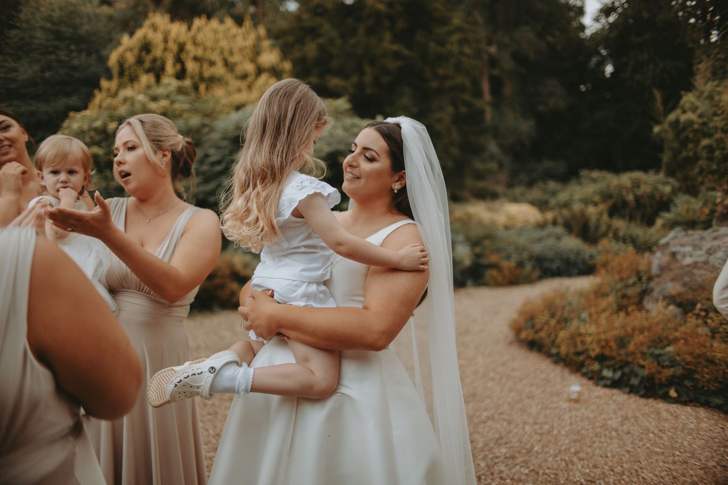 A tender moment shared among wedding attendees in neutral-colored dresses.