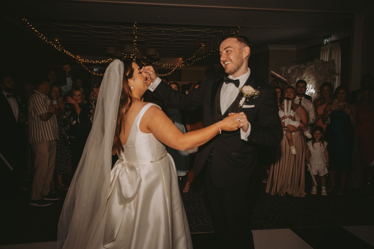 A couple sharing their first dance at a dimly lit wedding reception.
