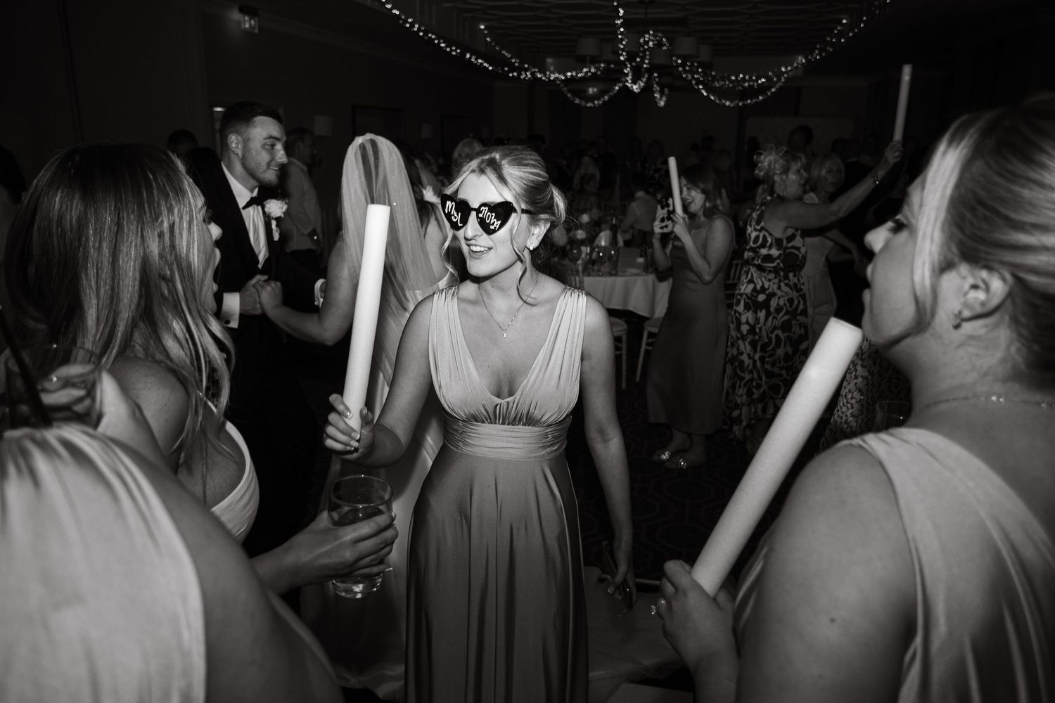 Wedding reception dance floor filled with guests celebrating under string lights.