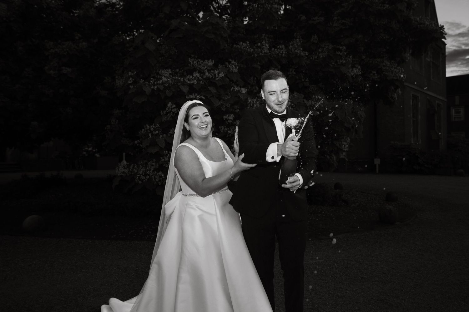 Couple shares joyful dance moment during evening wedding reception.