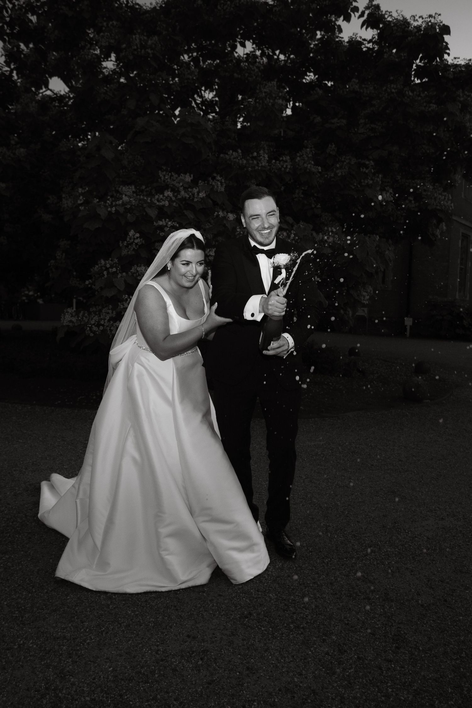 A celebratory moment with champagne in formal attire against a dark outdoor backdrop.