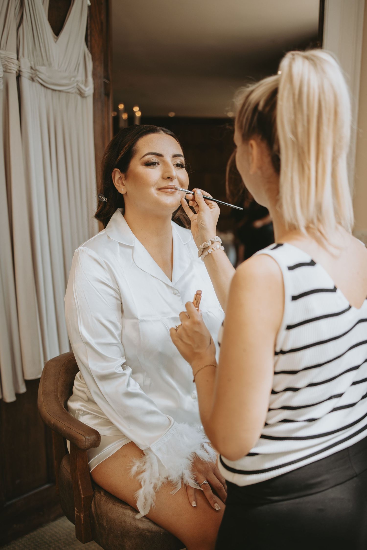 Wedding preparation scene with makeup being applied in a warmly lit room.