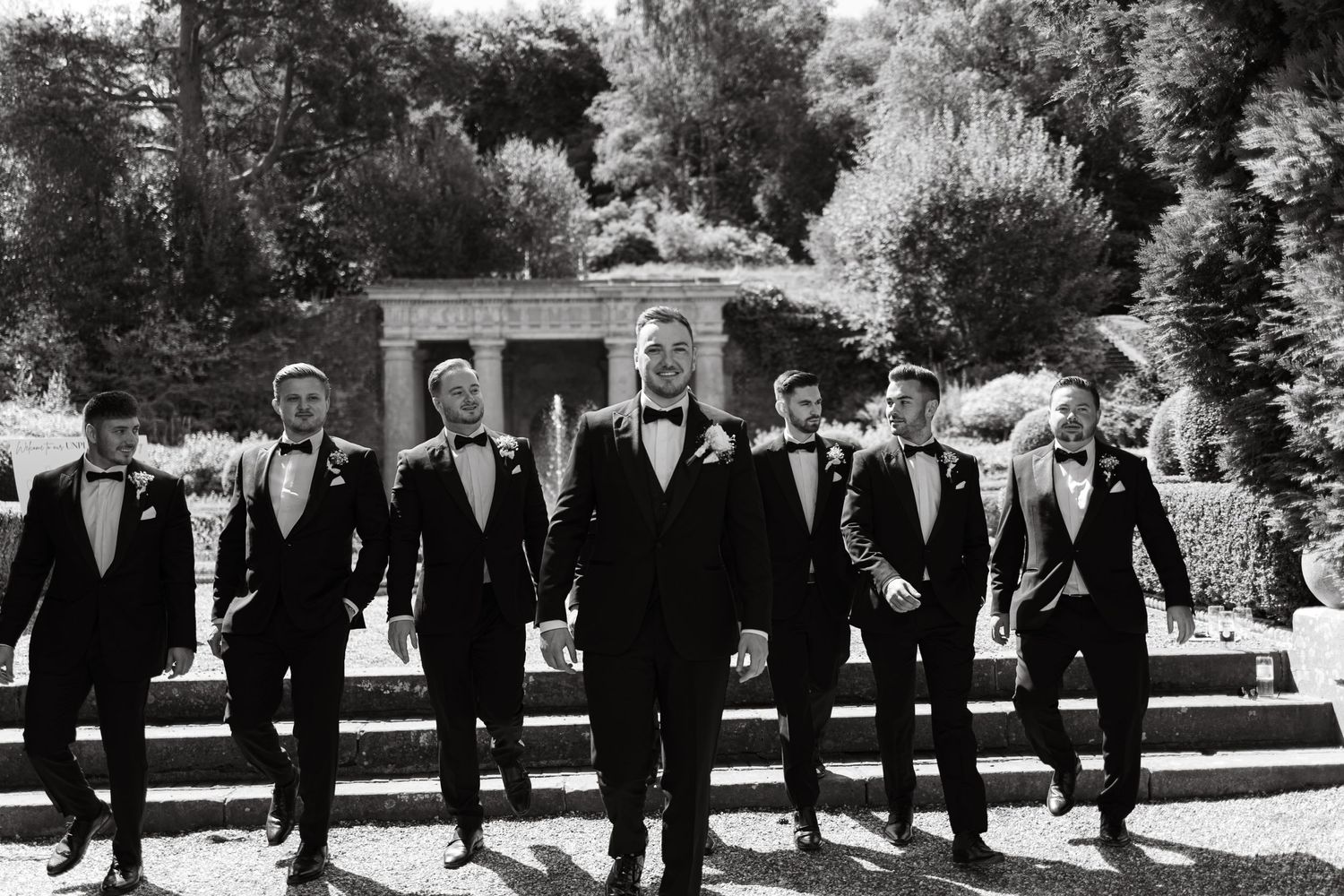 Groomsmen in black tuxedos walk together outdoors in a candid wedding photo sequence.
