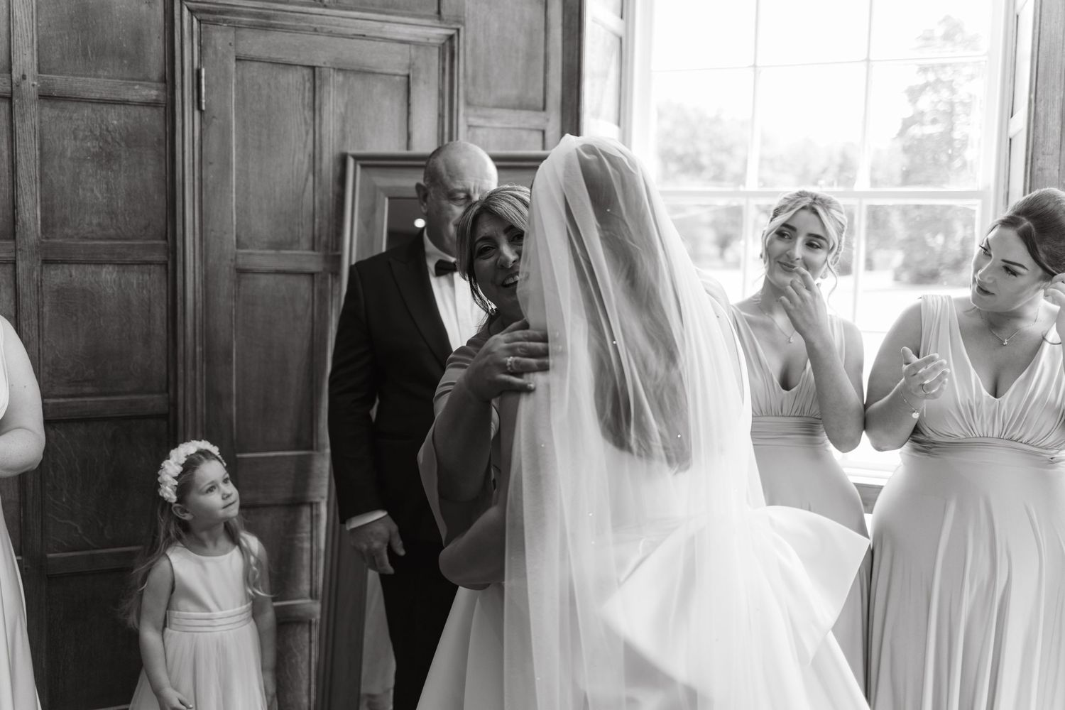 Wedding party members in a bright room sharing emotional moments before the ceremony.