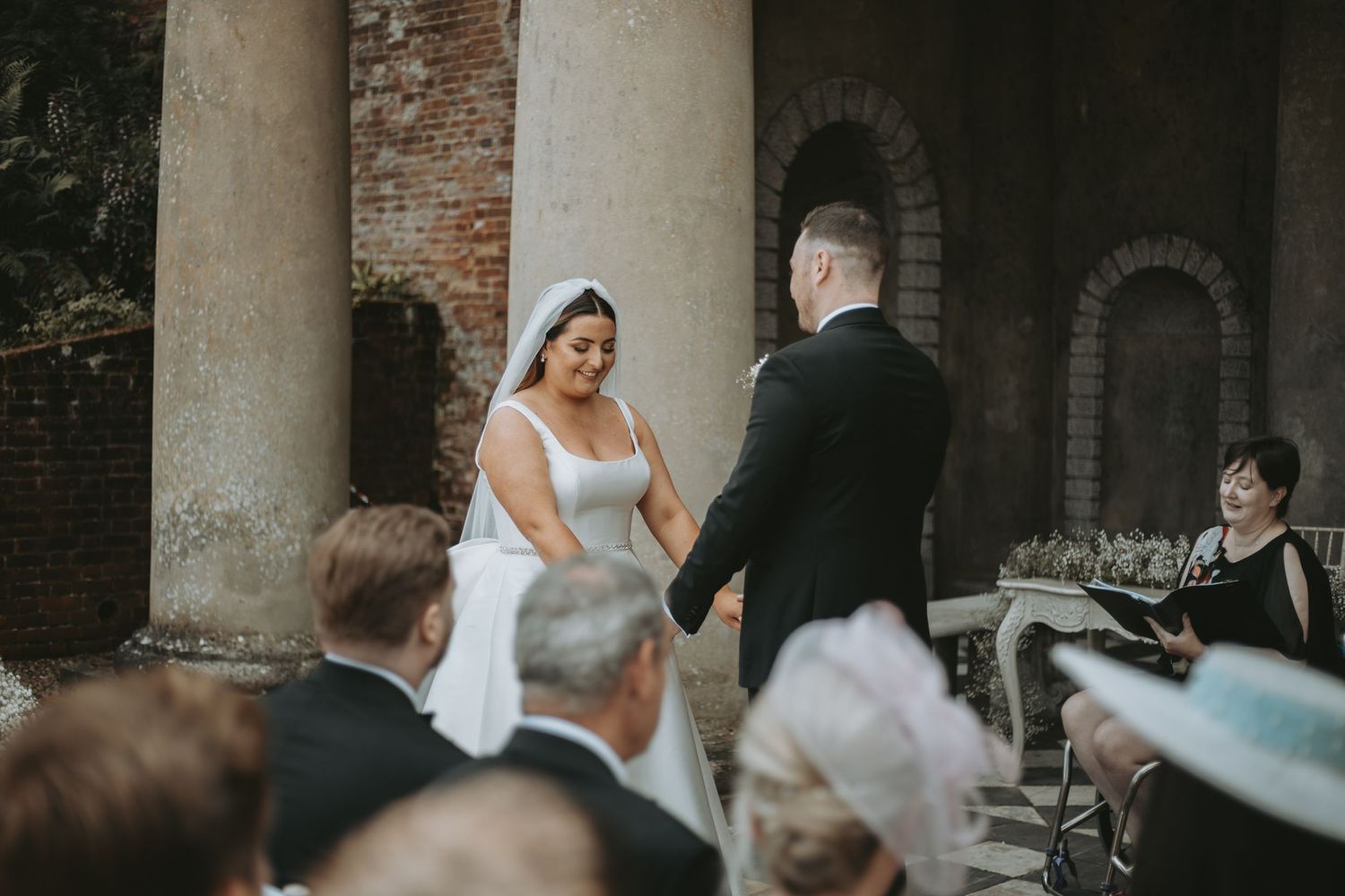 Wedding ceremony taking place in a historic brick colonnade setting.