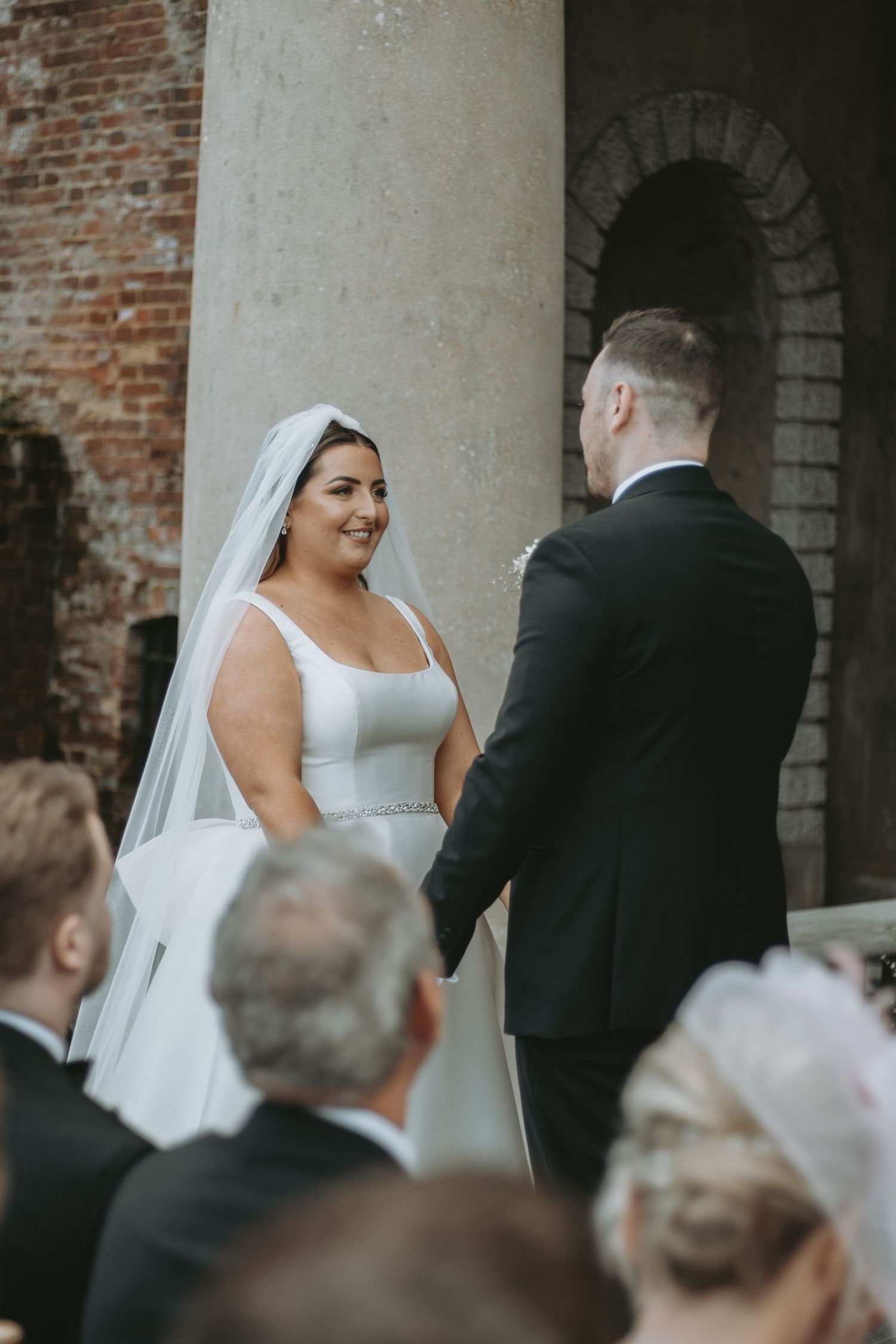Wedding ceremony moments captured against rustic brick columns and archways.