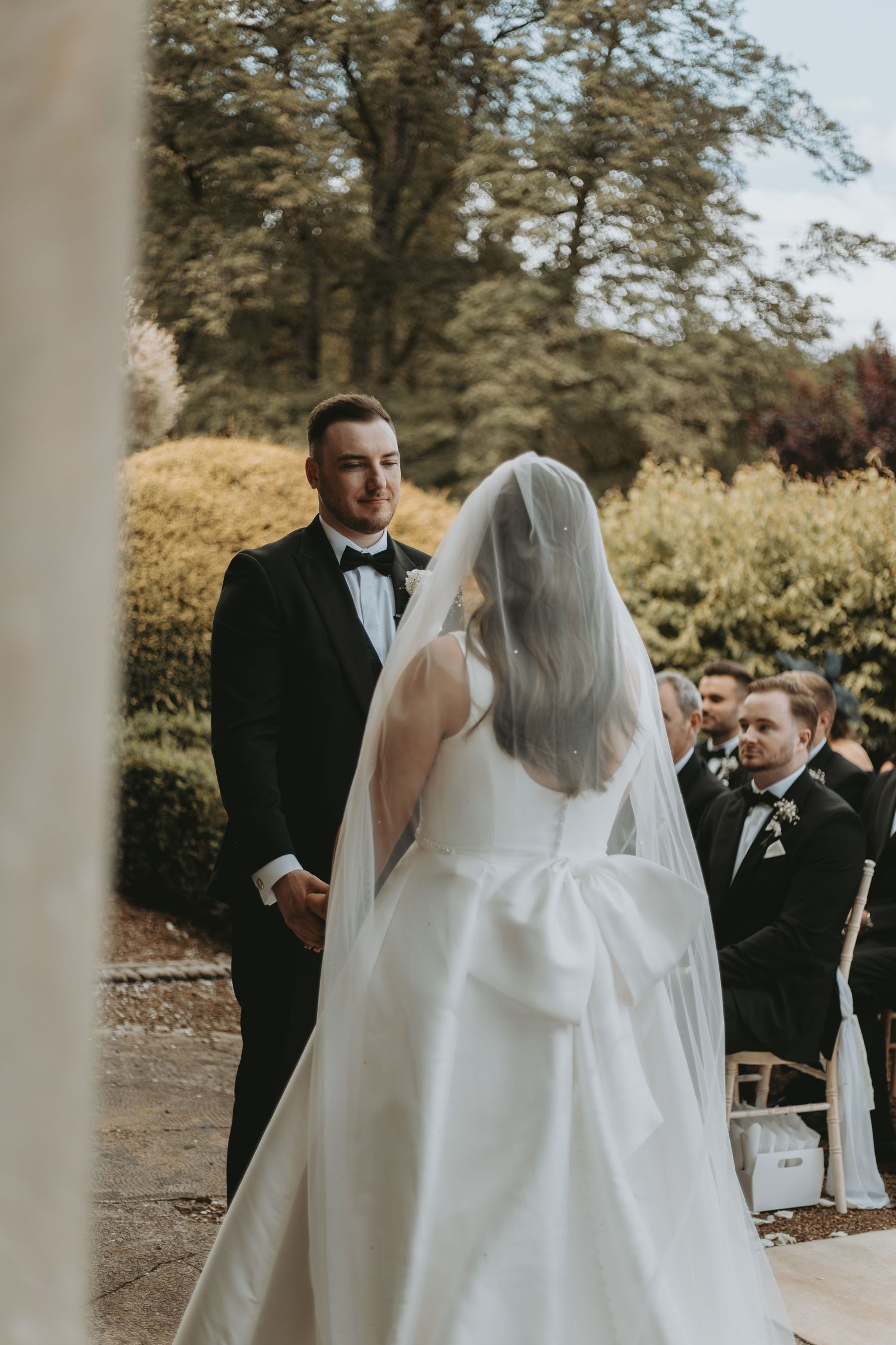 Outdoor wedding ceremony with flowing white dress and veil against a backdrop of autumn trees.