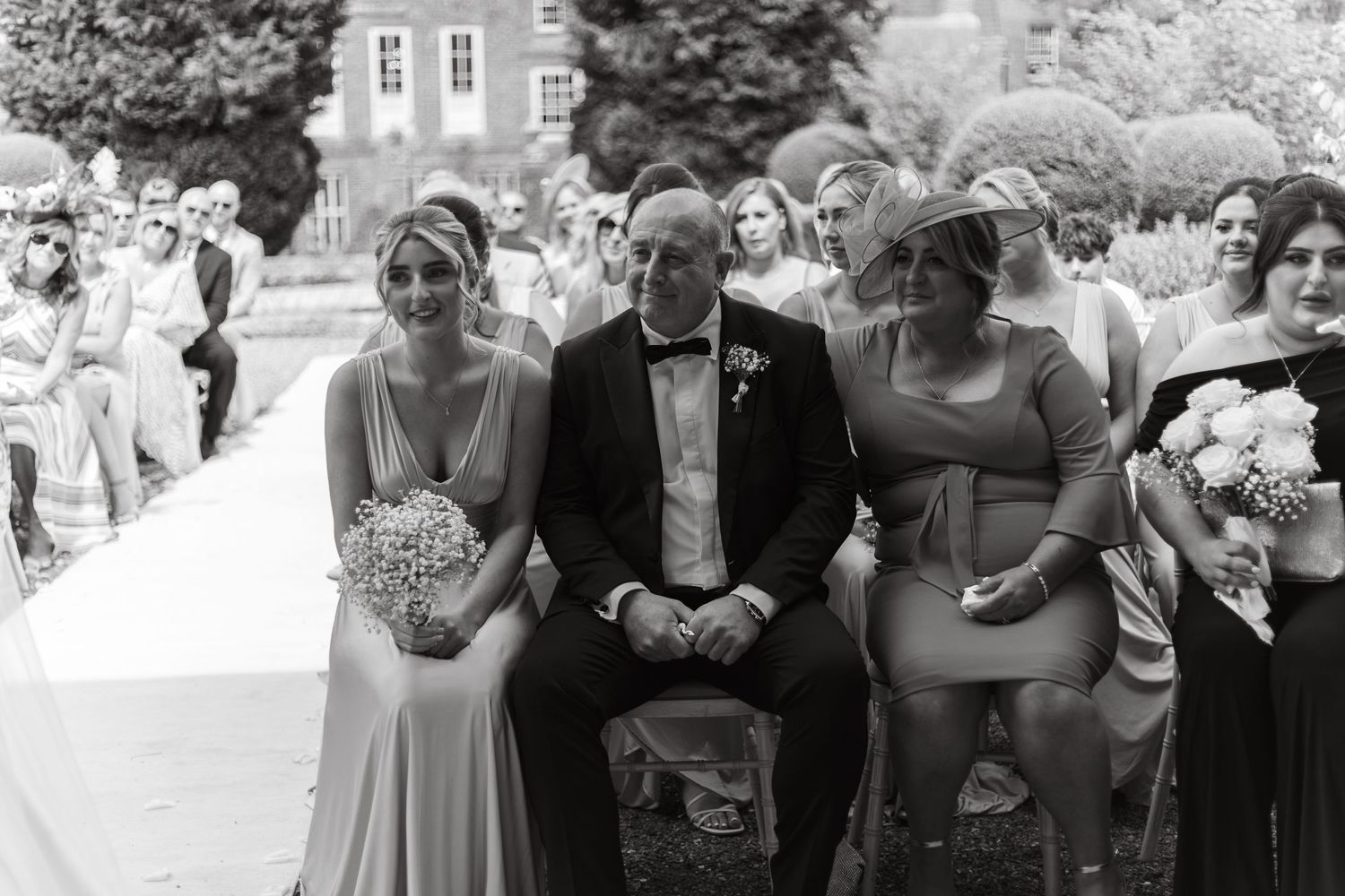 Wedding guests gathered outdoors on a sunny day watching the ceremony unfold.