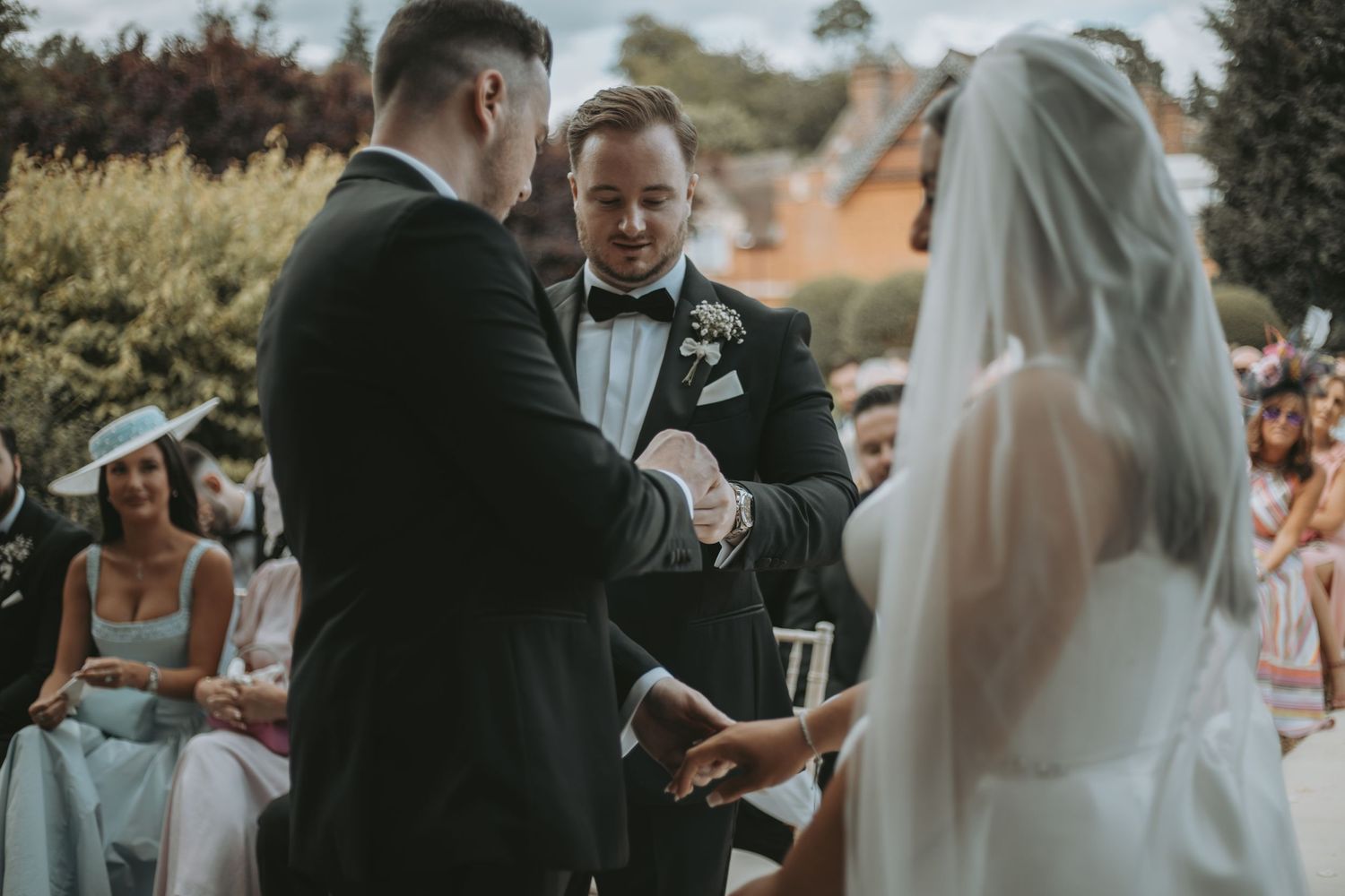 Wedding ceremony guests gather outdoors under natural lighting during an intimate celebration.