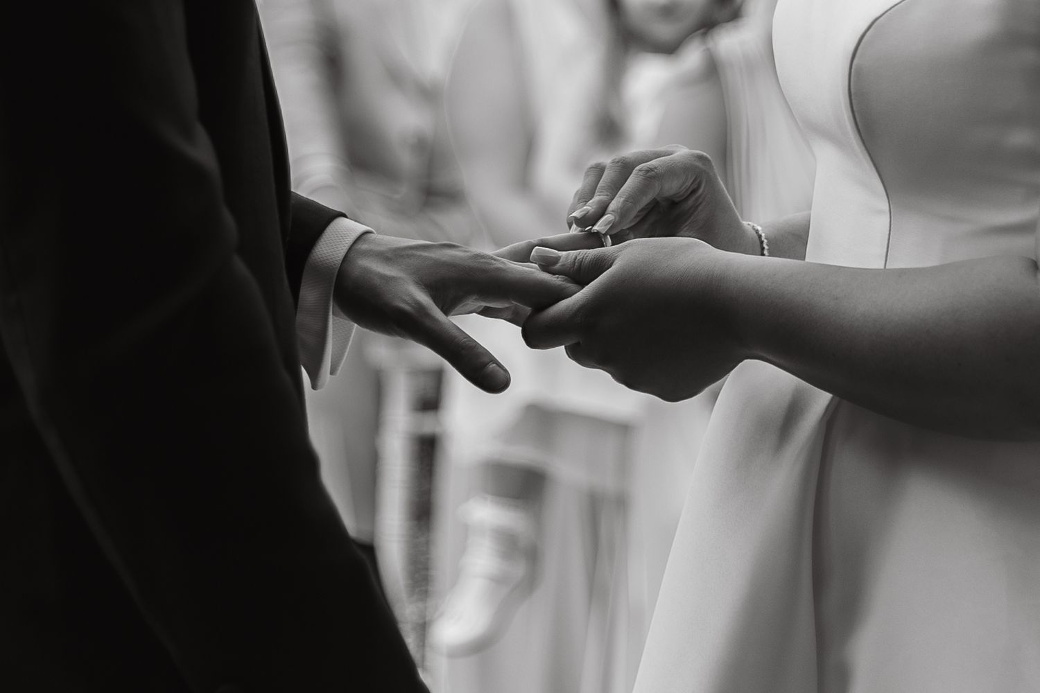 Close-up shot of wedding rings being exchanged during the ceremony.