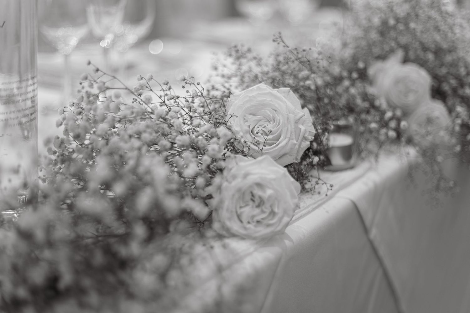 Soft focus floral arrangements featuring roses and baby's breath in wedding decor.