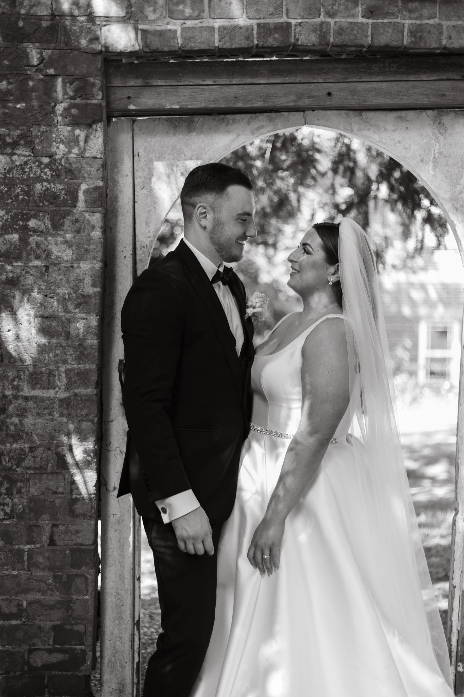 Wedding couple sharing intimate moments against a rustic brick wall backdrop.