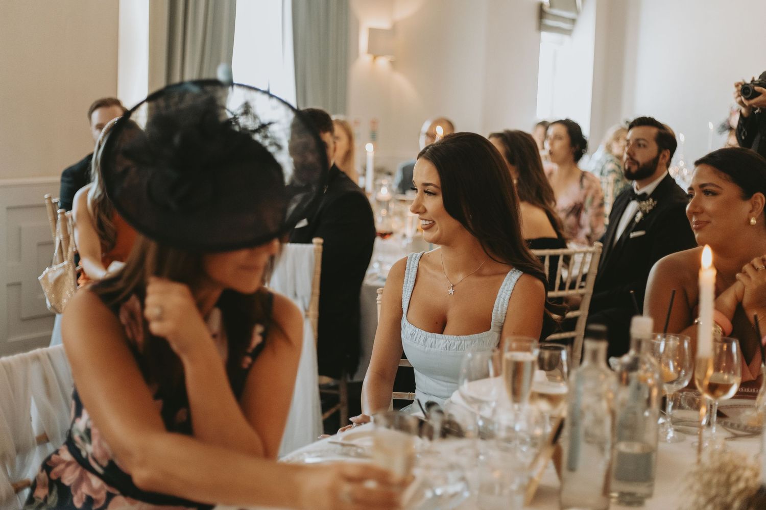 Emotional reactions from wedding guests during reception speeches in elegant white venue.