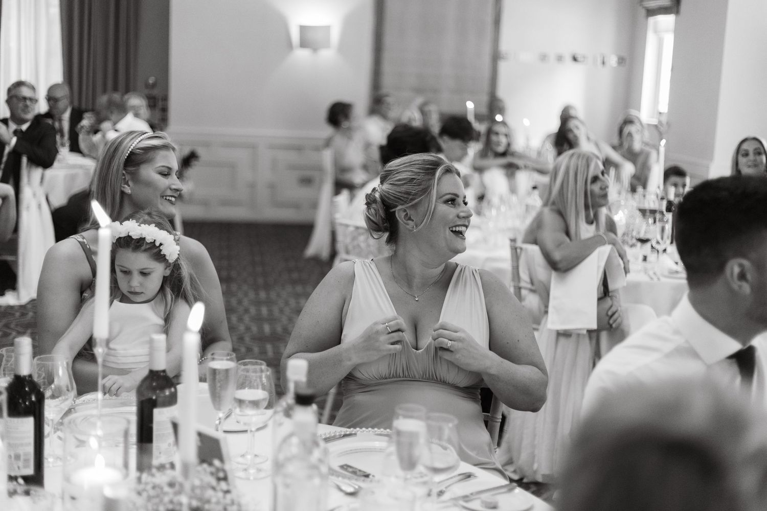 Wedding reception guests react emotionally during speeches at candlelit dinner.