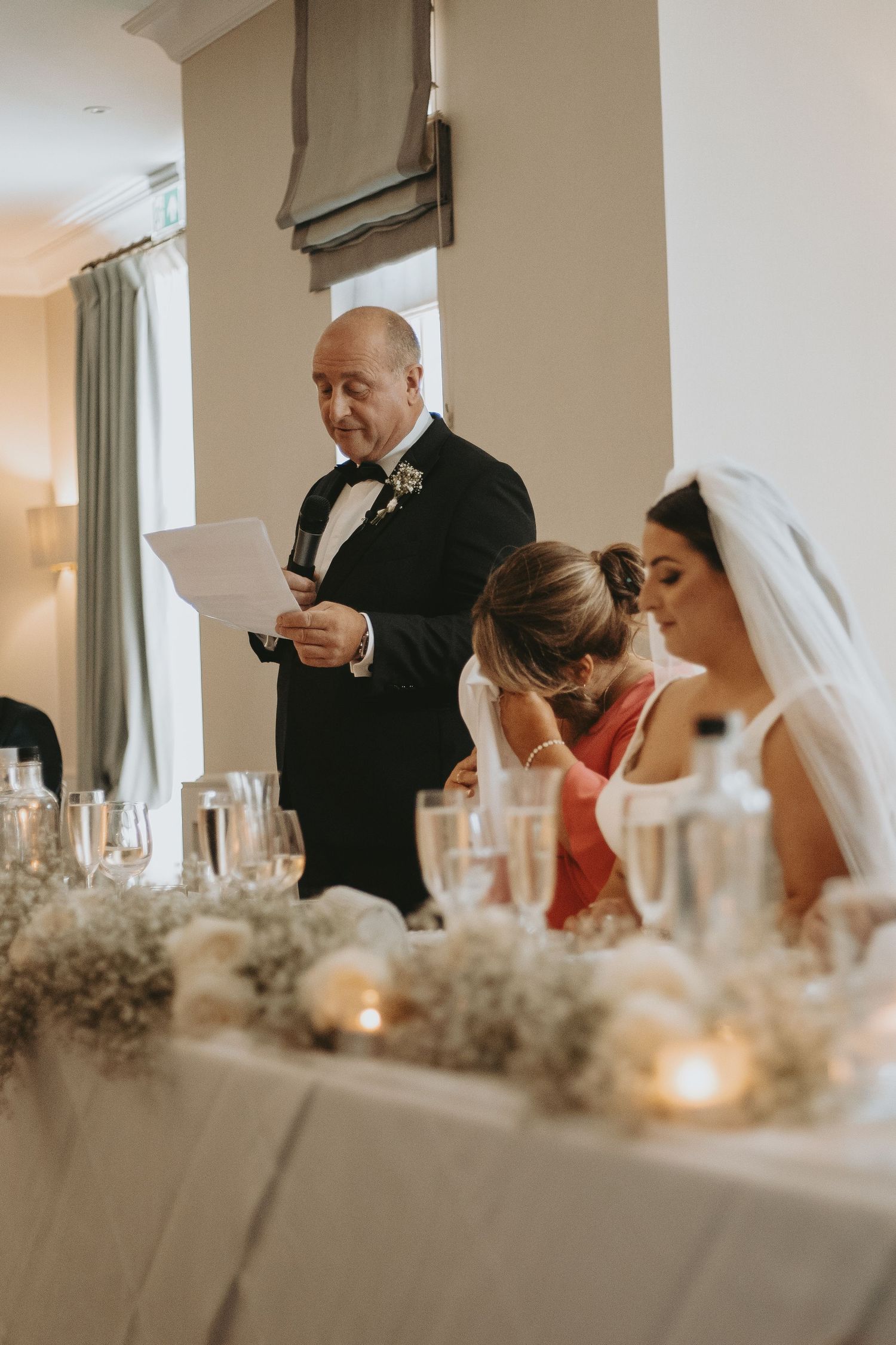 Wedding reception dinner scene with formal attire and elegant table settings.