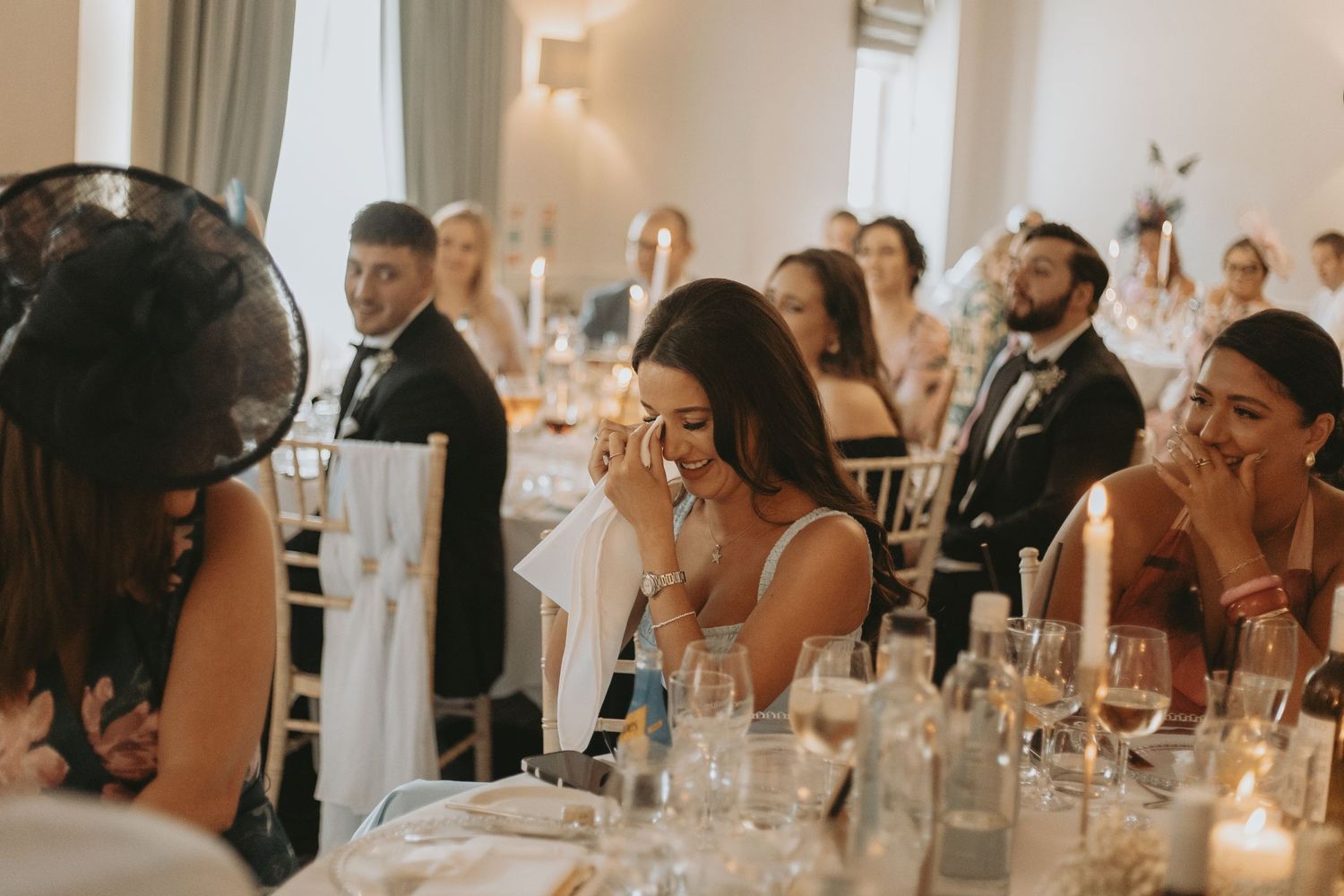 Wedding guests listen intently during reception speeches at elegant venue.