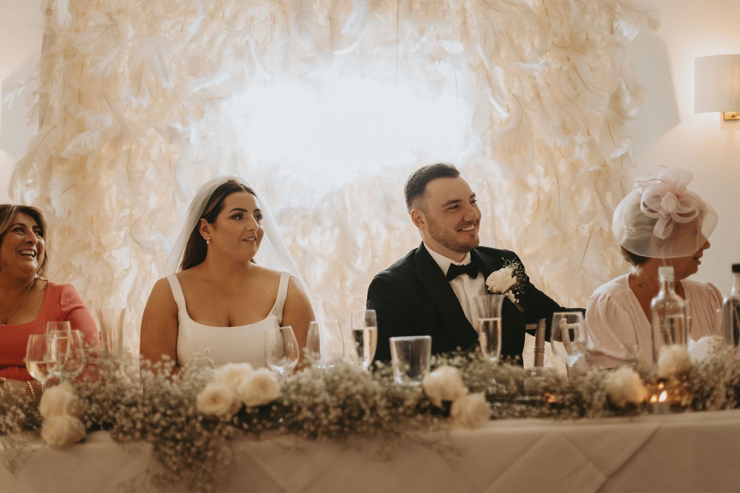Wedding reception table decorated with soft lighting and floral arrangements in neutral tones.