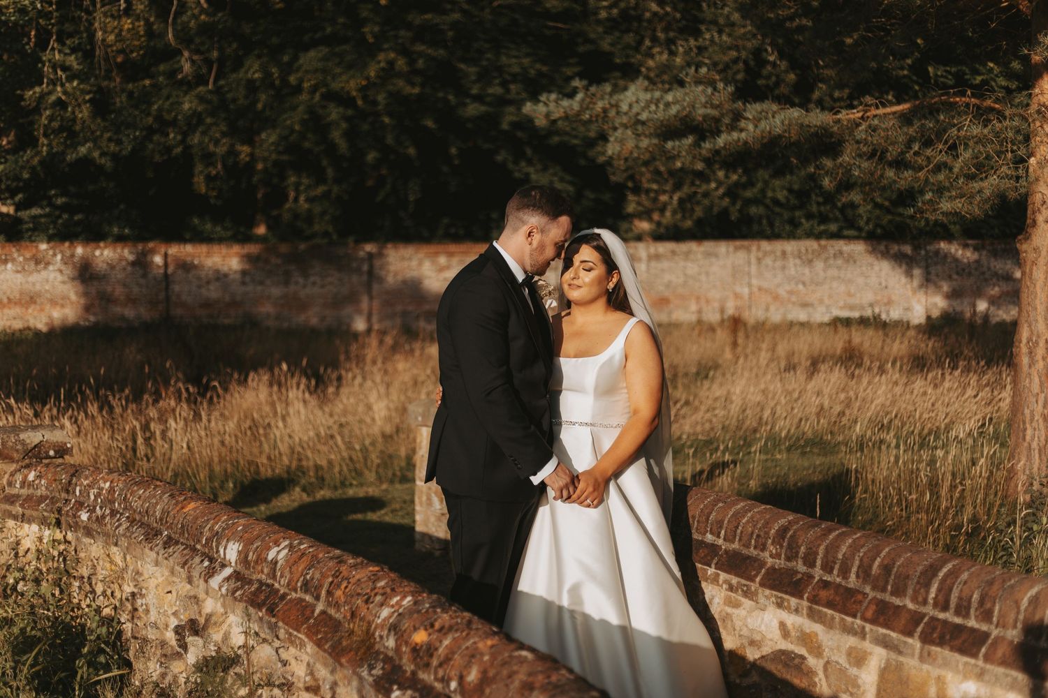 Romantic sunset wedding portraits against rustic brick architecture.