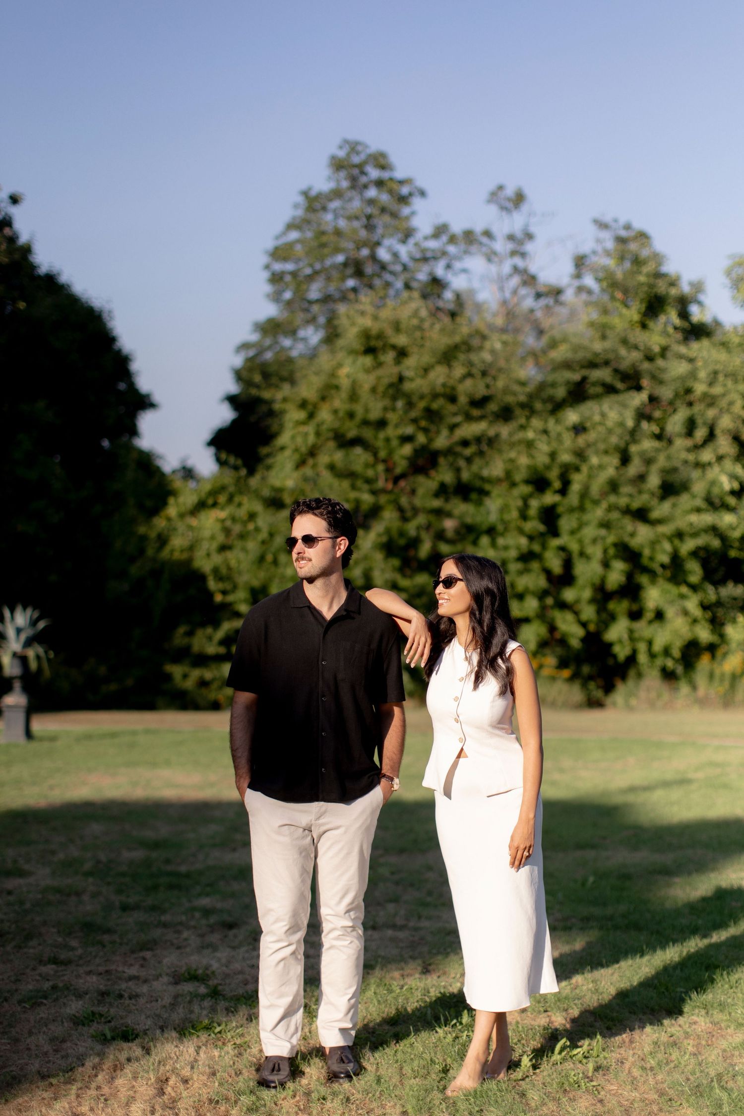Stylish couple walking together on a sunny day in a park setting.
