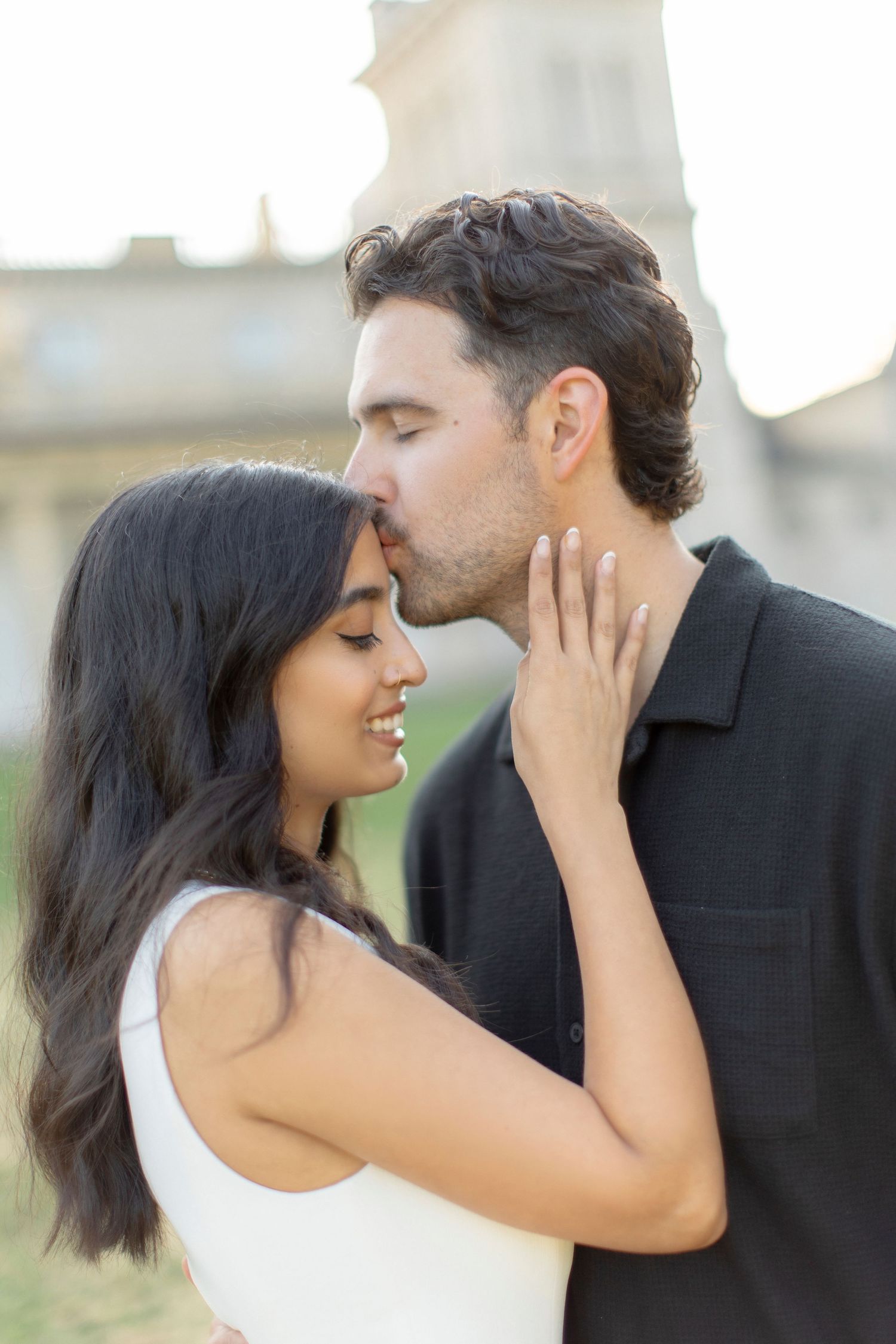 Romantic couple sharing an intimate moment in front of a historic mansion at sunset.