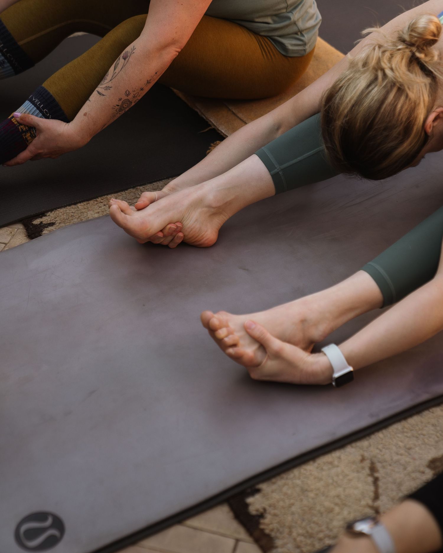 Close-up of hands and feet on yoga mats during stretching exercises.