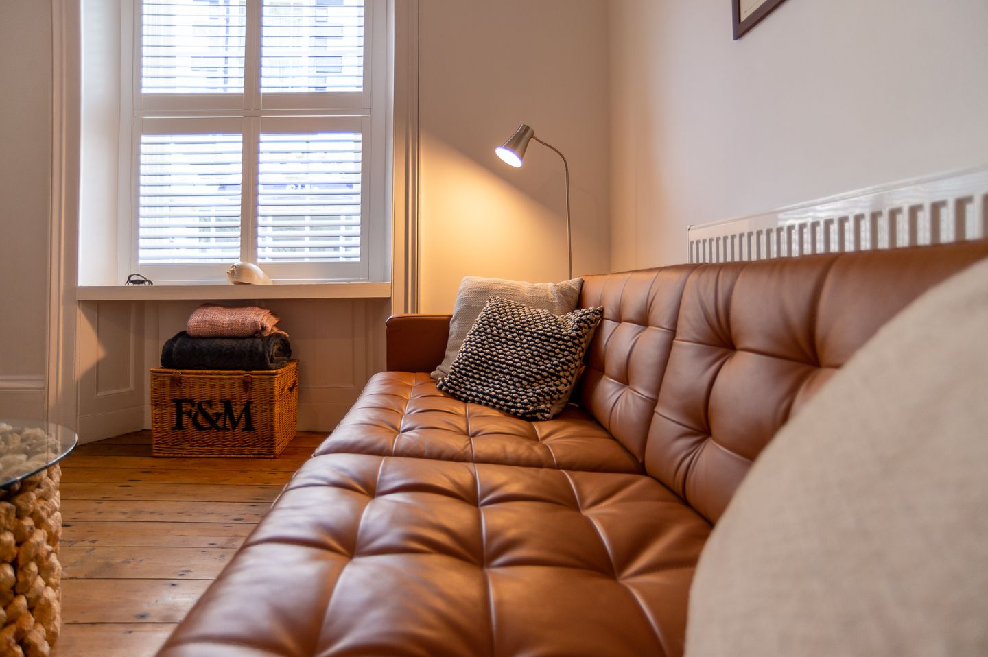 Cozy sofa lounge scene captured across a leather sofa, with natural window light pouring in, showcasing a relaxed and inviting atmosphere
