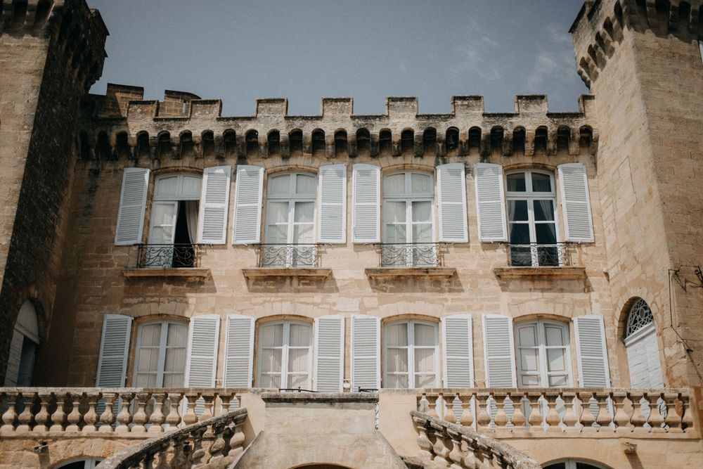 Historic castle facade with ornate windows and crenellated roofline in sunlight.