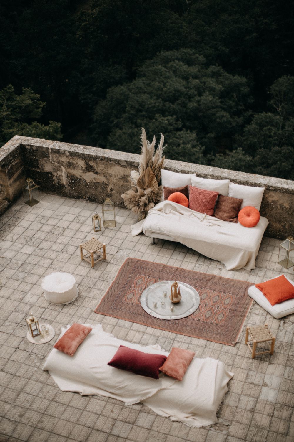 Cozy outdoor lounge area with white couches and terracotta accents on stone terrace.