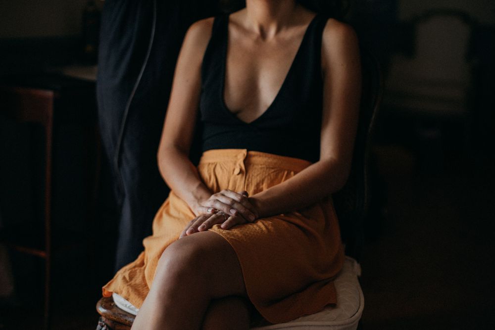 Person sitting in casual attire against dark background in moody lighting.