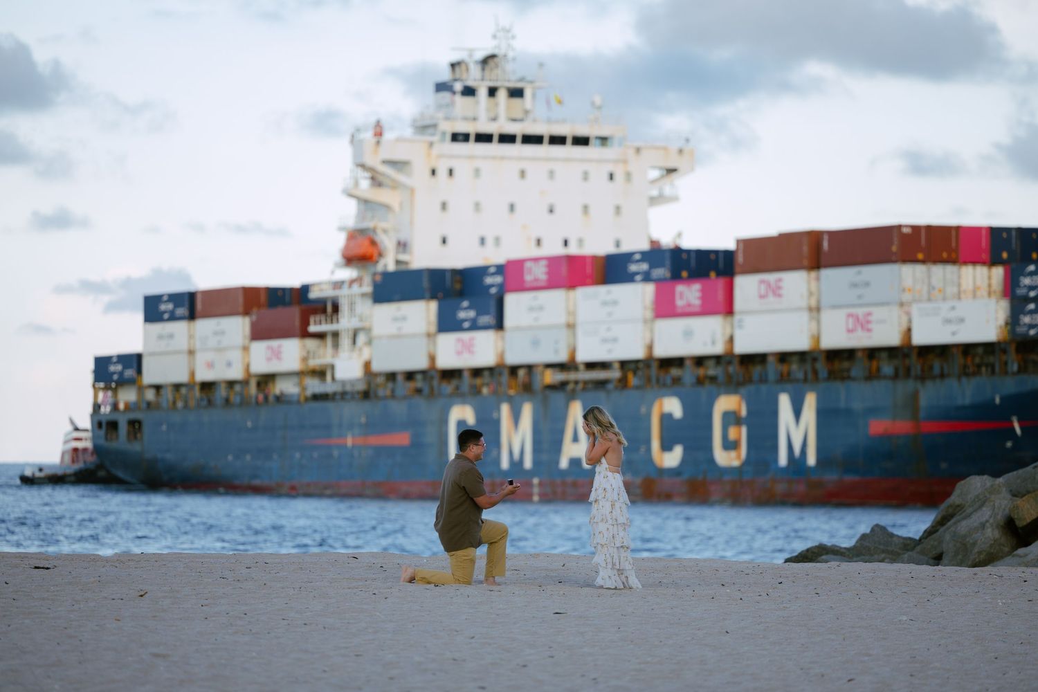 dramatic romantic engagement photoshoot pictures in FORT lauderdale beach, taken by wanderlust studios with a cargo ship. behind the couple