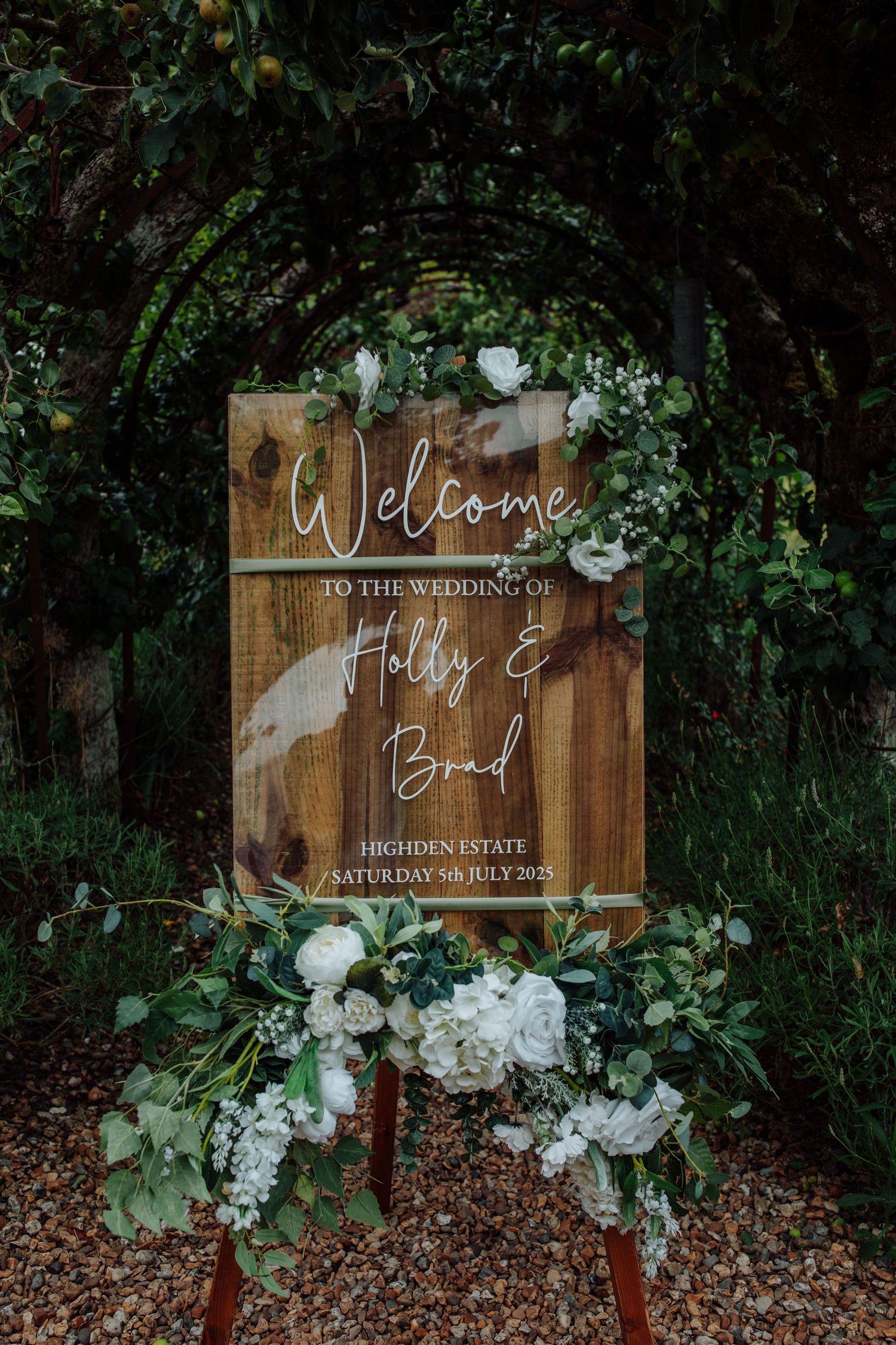 Elegant wooden ceremony chairs with white cushions arranged outdoors featuring a 'Reserved for Family' sign on one seat.