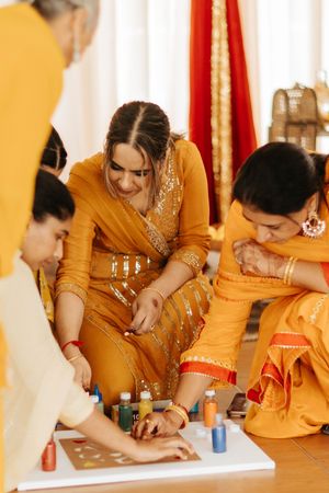 People in traditional yellow Indian attire participate in a wedding ritual during a pre-wedding ceremony.