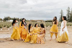 Wedding party wearing coordinated yellow outfits poses together on rustic outdoor terrain.