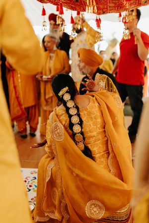 Ornate yellow and gold traditional Indian wedding attire with detailed embroidery shown from behind during celebration.