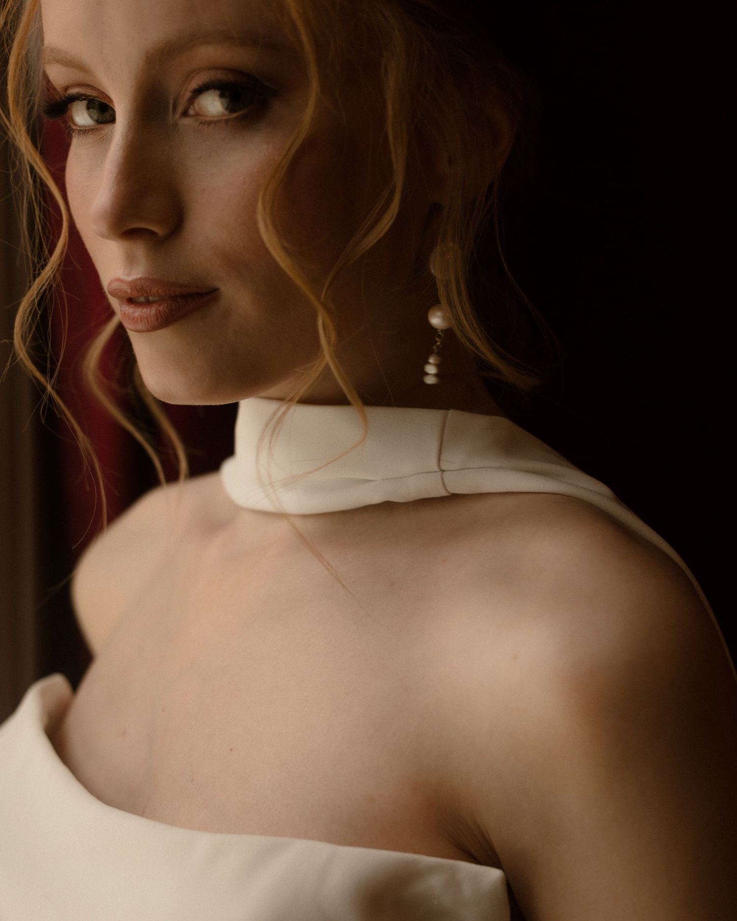 Artistic portrait series showing bare shoulders and neckline against a dark background with soft, moody lighting.