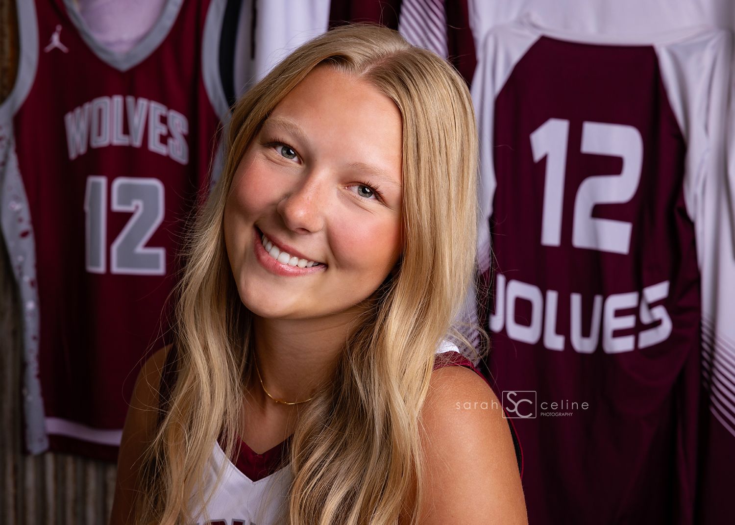 High school senior portrait session taken against brick wall and sports jerseys.