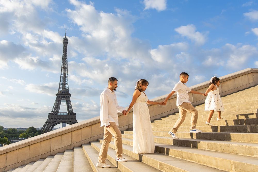A group in white and beige outfits walks up stone steps at Trocadero Square with the Eiffel Tower in the background.