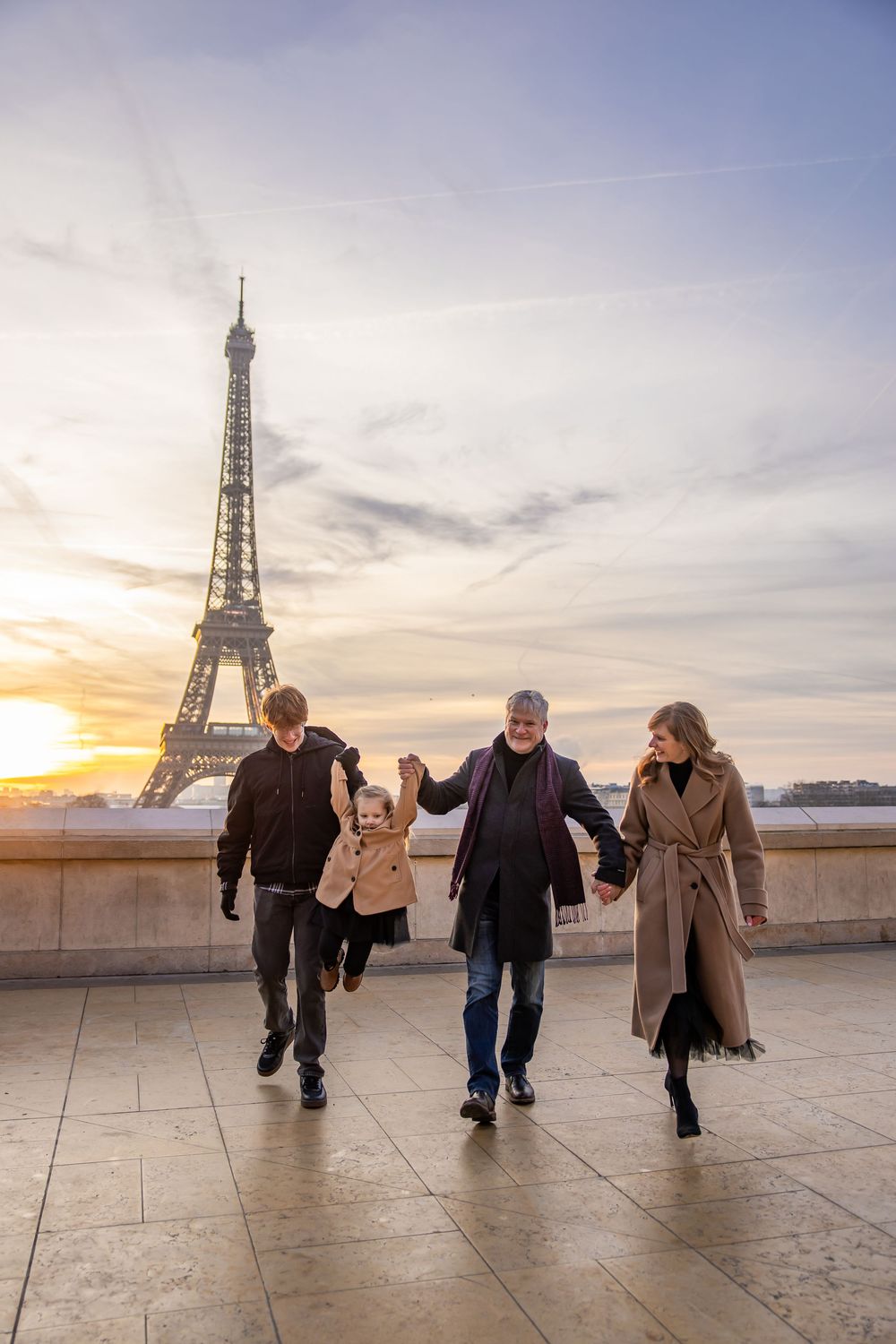 A group of friends walk together during sunset with the iconic Eiffel Tower in the background in Paris, France.