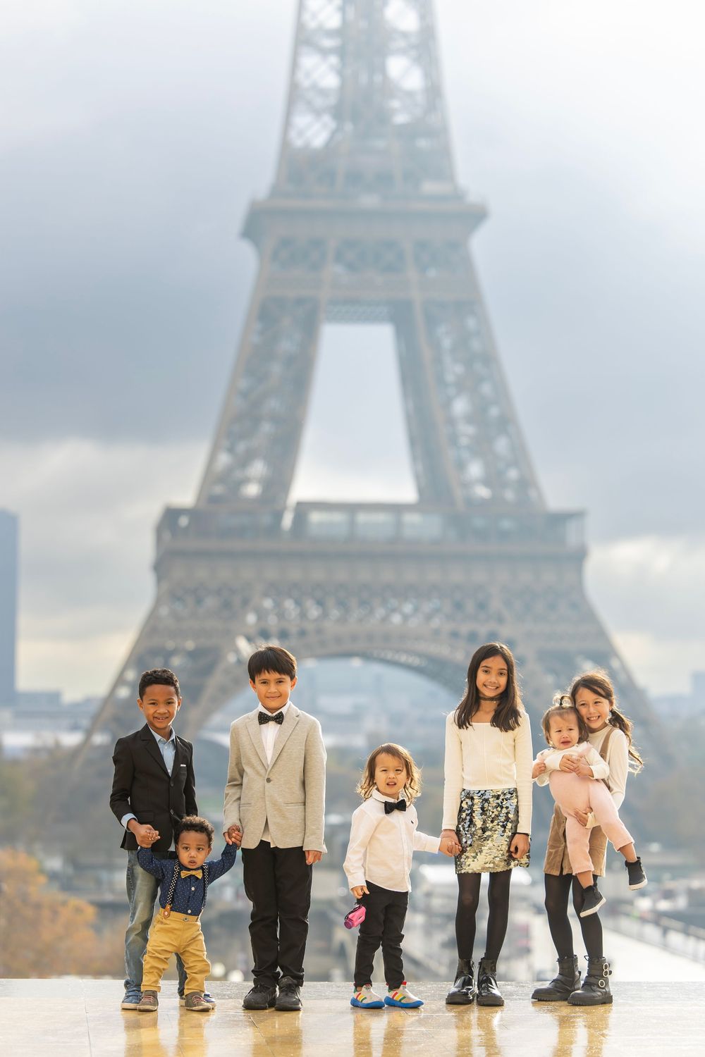 A family poses together on a misty autumn day with the iconic Eiffel Tower rising majestically in the background in Paris.