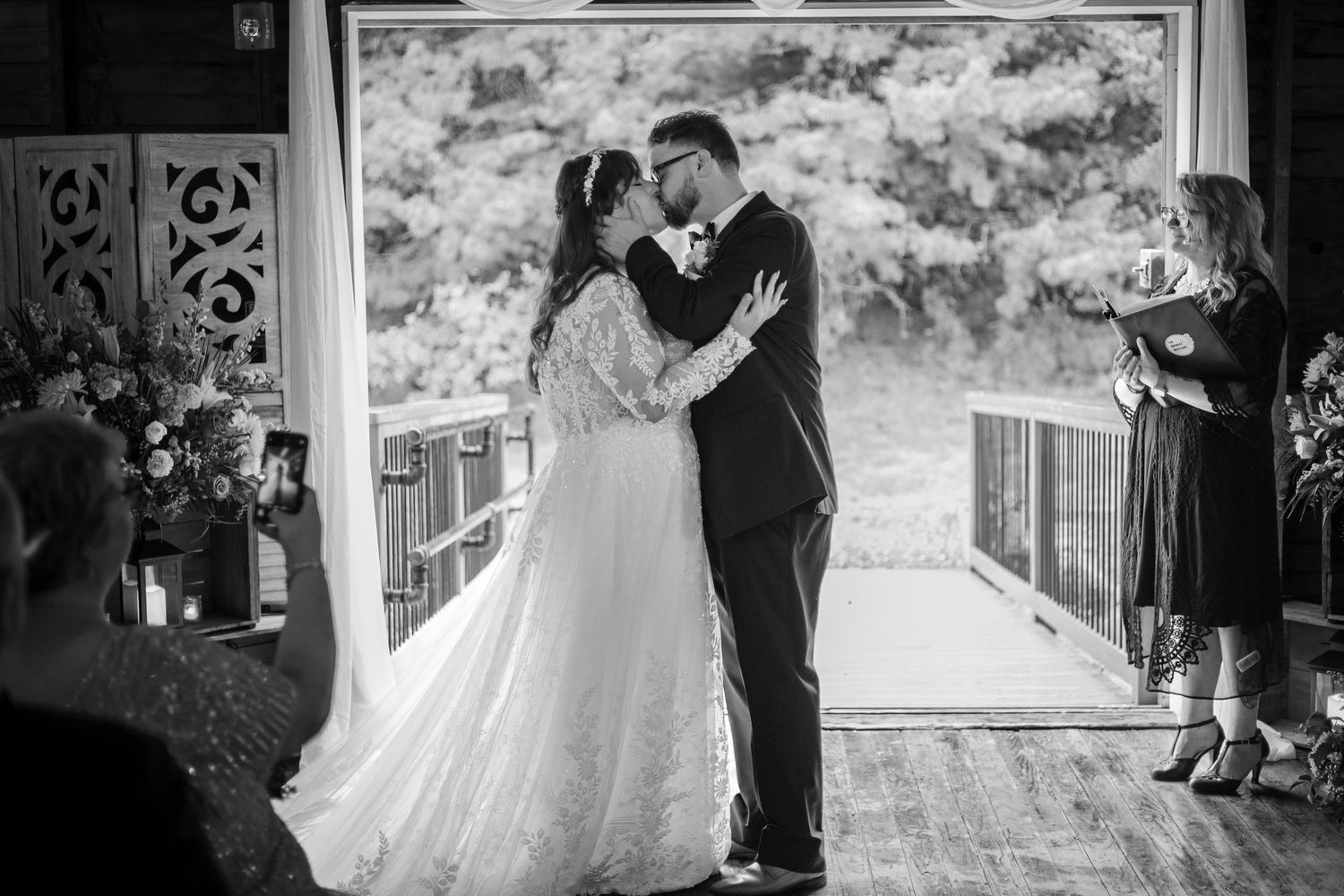 A romantic black and white photograph of a couple in their wedding attire sharing a special moment at a rustic venue.