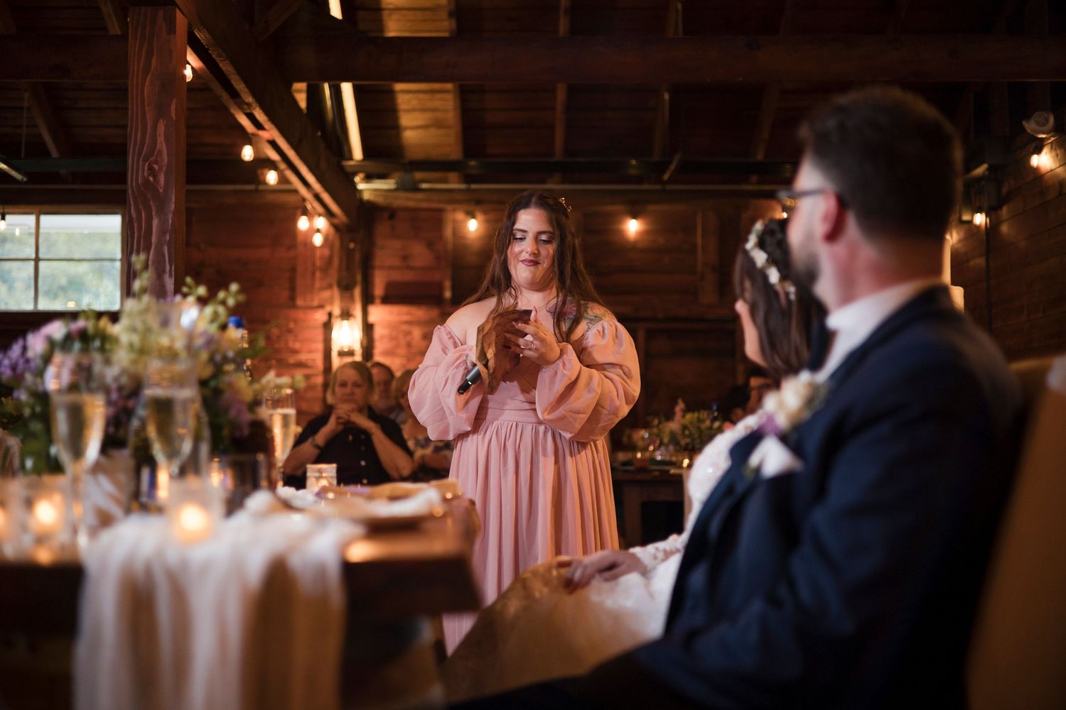 Wedding couple shares a romantic dance under warm lighting at a rustic barn reception.