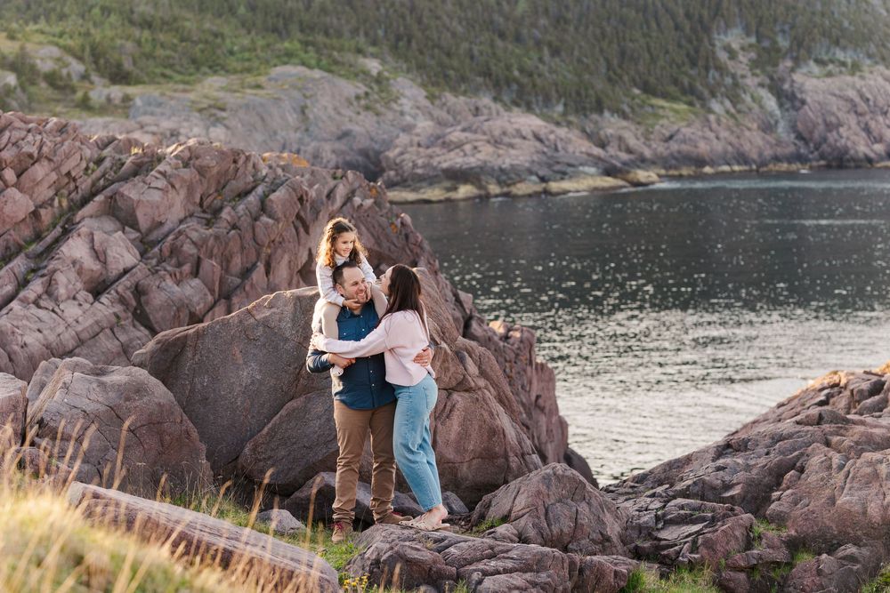 Romantic couple exploring rocky coastal cliffs overlooking a serene ocean bay in St. John's, Newfoundland.