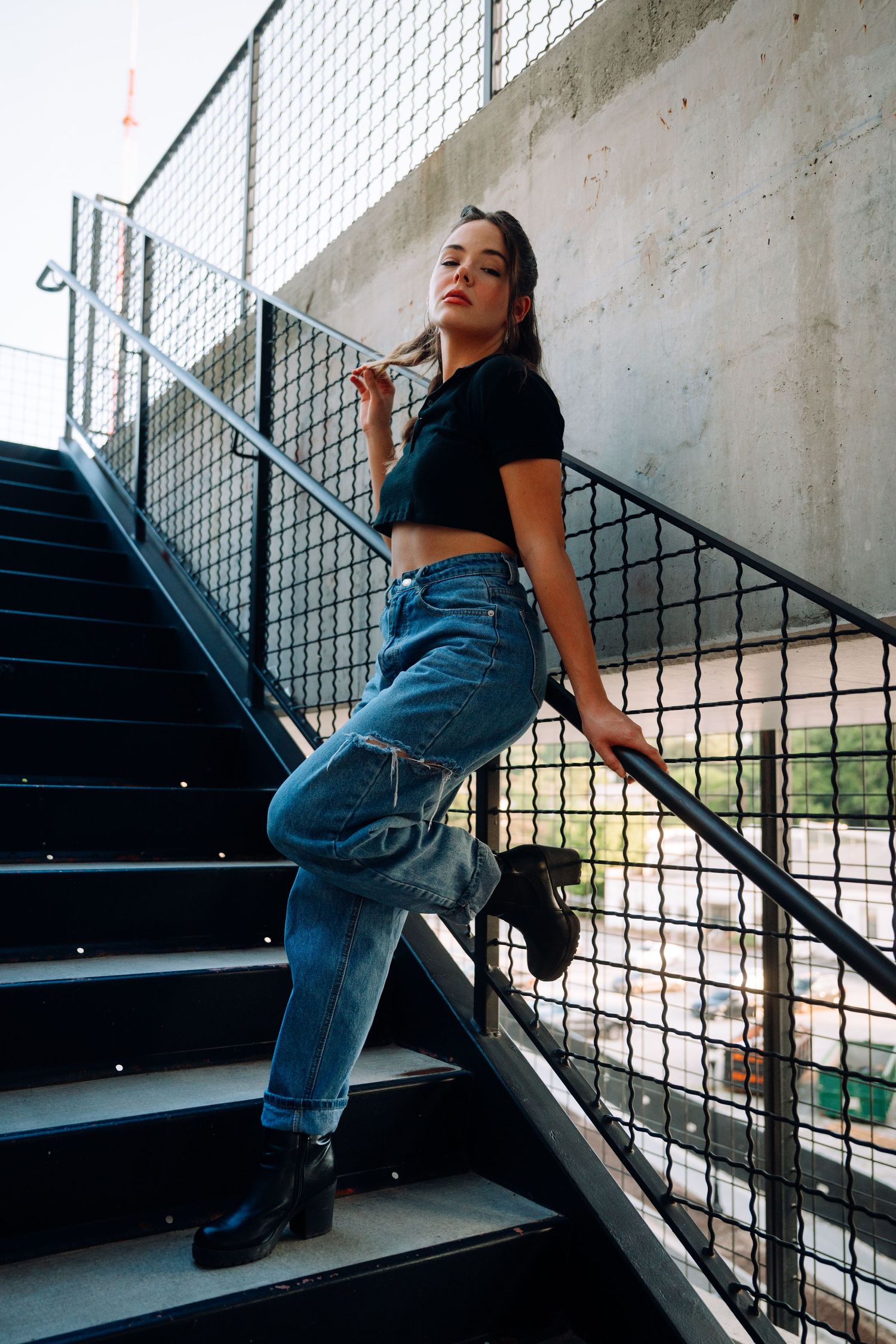 Dynamic poses captured on black metal stairs with concrete wall backdrop.